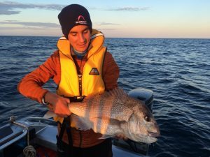 Man holding a snapper fish and smiling